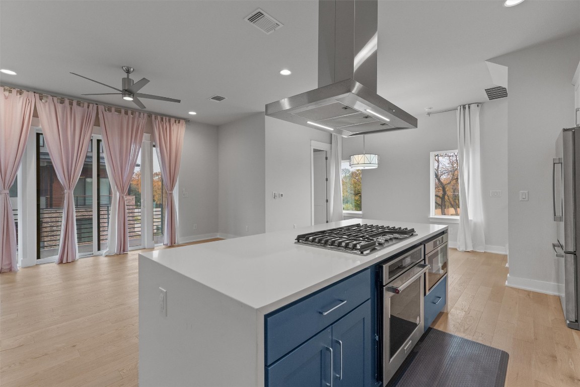 5002 Pecan Springs Road, Unit 1 Austin, TX 78723 - Photo 15 of 38 Kitchen with island range hood, light wood-style flooring, a center island, appliances with stainless steel finishes, and recessed lighting