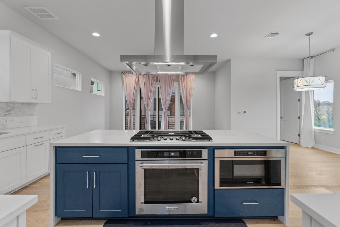 5002 Pecan Springs Road, Unit 1 Austin, TX 78723 - Photo 16 of 38 Kitchen featuring blue cabinetry, extractor fan, appliances with stainless steel finishes, white cabinetry, and recessed lighting