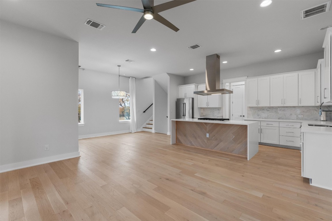 5002 Pecan Springs Road, Unit 1 Austin, TX 78723 - Photo 36 of 38 Kitchen featuring white cabinetry, a center island, island exhaust hood, light wood finished floors, and open floor plan