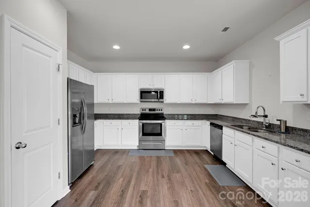a kitchen with granite countertop a refrigerator and a stove top oven
