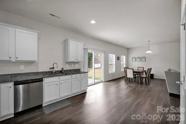 a large white kitchen with chairs and wooden floor