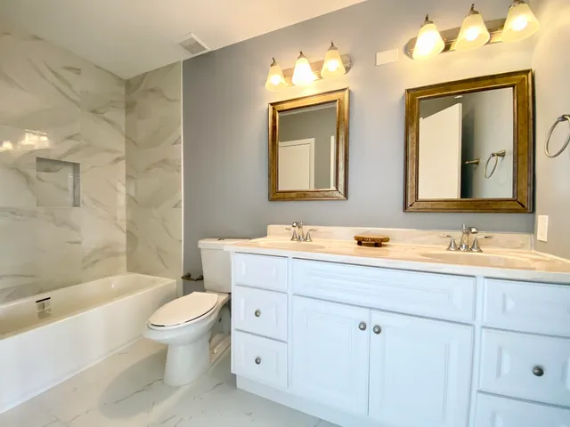 a bathroom with a toilet a sink a tub and mirror