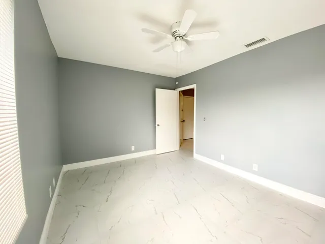 an empty room with a ceiling fan and a window