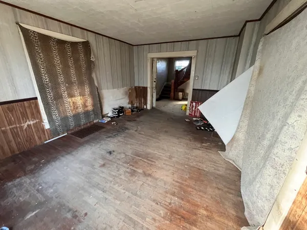 a view of an empty room with wooden floor and stairs