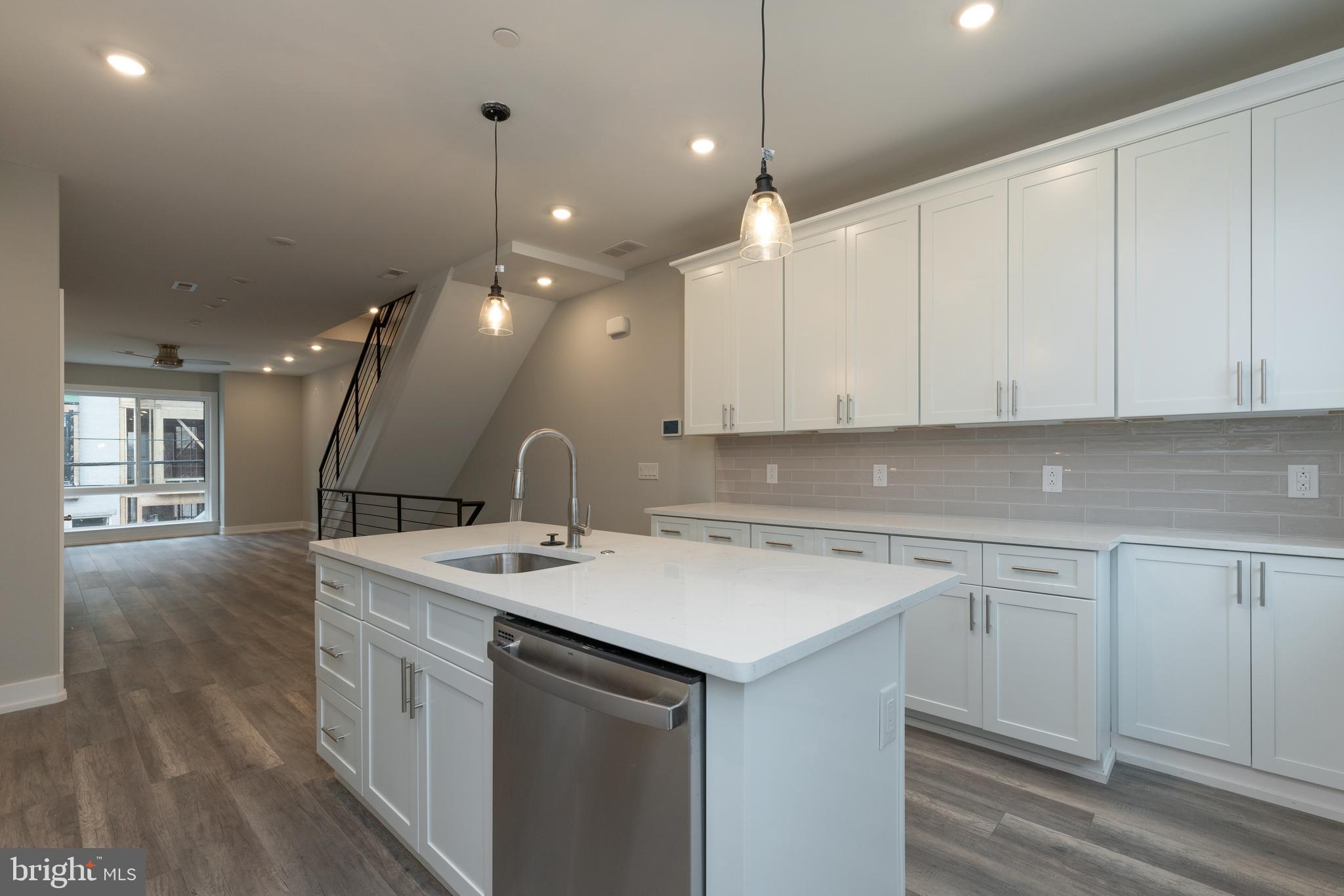 135 West Huntingdon Street, Unit 2 Philadelphia, PA 19133 - Photo 5 of 29 a kitchen that has a sink a microwave oven a stove and white cabinets with wooden floor