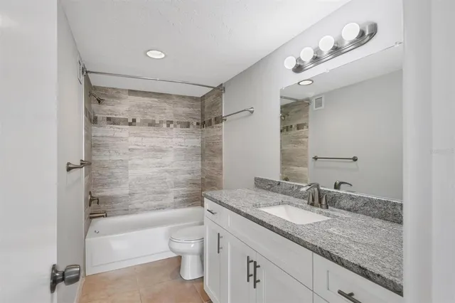 a bathroom with a granite countertop sink a toilet and shower