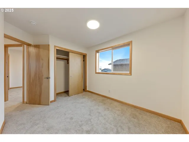 a view of an empty room with closet and a window