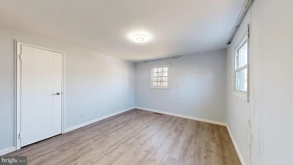 a view of an empty room with wooden floor and closet