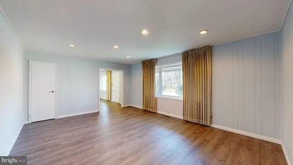 a view of an empty room with wooden floor and window