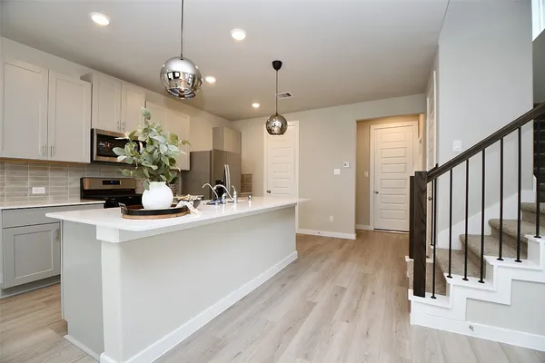 a kitchen with kitchen island granite countertop a stove a sink and white cabinets with wooden floor