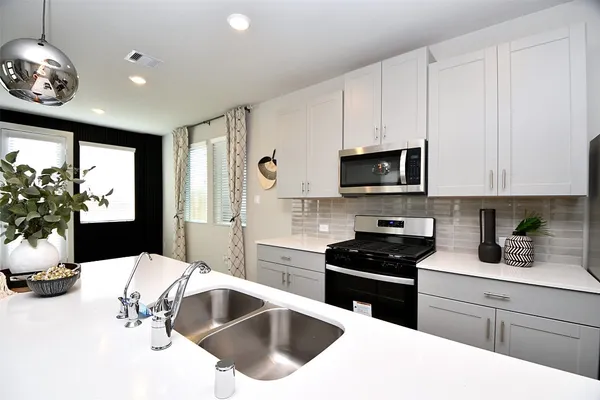 a kitchen with granite countertop a sink stainless steel appliances and white cabinets