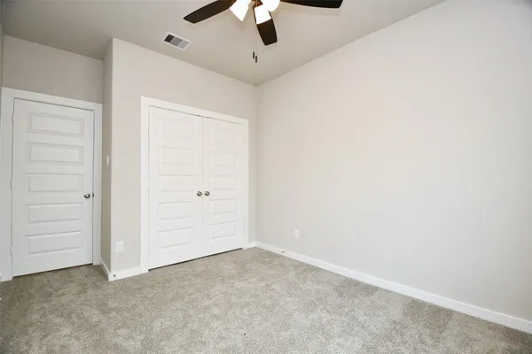 an empty room with closet and a ceiling fan