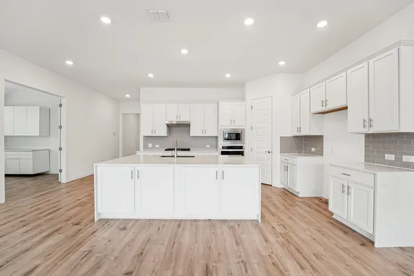 a large kitchen with stainless steel appliances granite countertop a large stove a sink dishwasher and a refrigerator with wooden floors