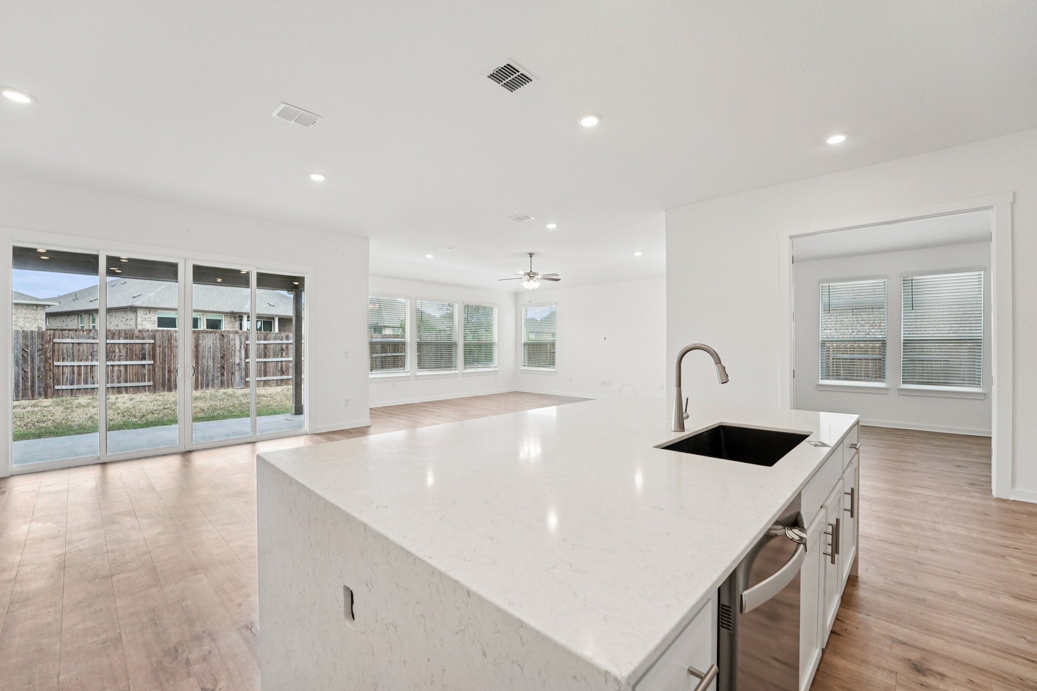 2233 Bravo Pass Leander, TX 78641 - Photo 32 of 33 Kitchen with a center island with sink, light stone countertops, white cabinets, open floor plan, and recessed lighting