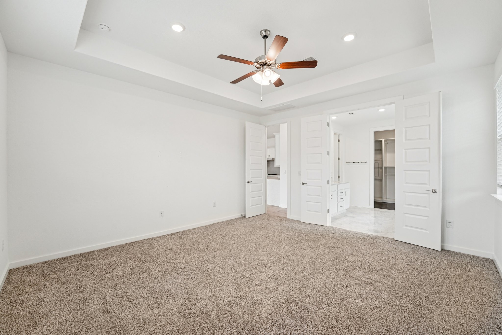 2233 Bravo Pass Leander, TX 78641 - Photo 29 of 33 Unfurnished bedroom with a tray ceiling, carpet floors, recessed lighting, ceiling fan, and ensuite bathroom