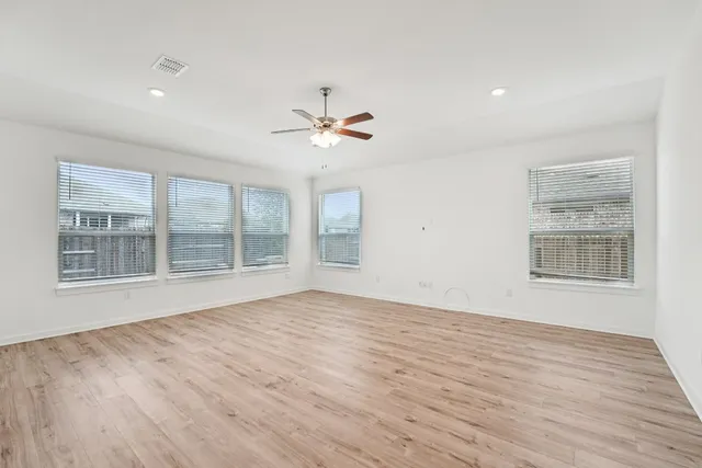 a view of an empty room with a window and wooden floor