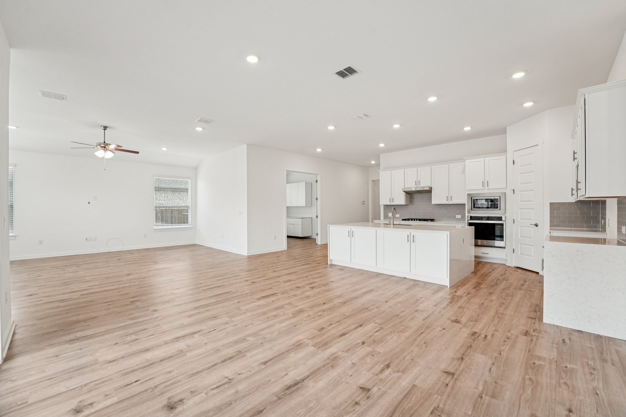 2233 Bravo Pass Leander, TX 78641 - Photo 30 of 33 Kitchen featuring open floor plan, decorative backsplash, white cabinetry, recessed lighting, and light wood-style floors