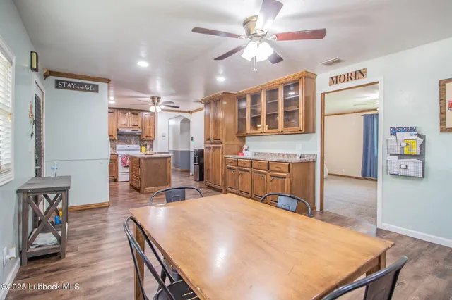 a open kitchen with kitchen island a stove a refrigerator a oven a sink dishwasher and white cabinets with wooden floor