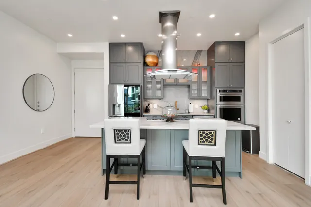 a kitchen with kitchen island stainless steel appliances a dining table chairs sink and cabinets