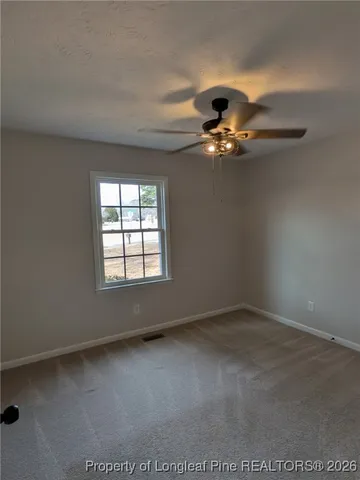 an empty room with a ceiling fan and window