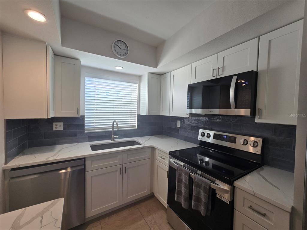 9200 Midnight Pass Road, Unit 10 Sarasota, FL 34242 - Photo 2 of 26 a kitchen with a sink stove top oven and microwave