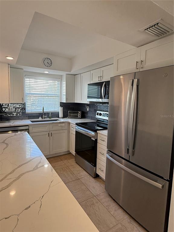 9200 Midnight Pass Road, Unit 10 Sarasota, FL 34242 - Photo 3 of 26 a kitchen with stainless steel appliances a refrigerator sink and cabinets