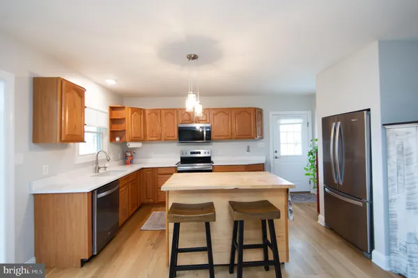 a kitchen with stainless steel appliances granite countertop a stove top oven a sink dishwasher a dining table and chairs with wooden floor