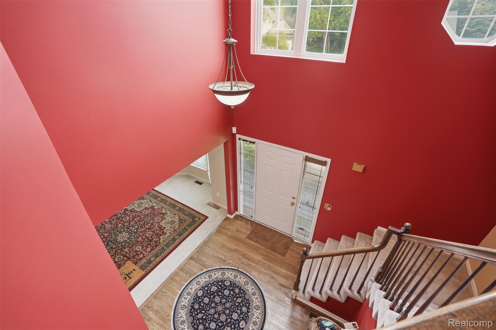170 Fairhill Way Howell, MI 48843 - Photo 26 of 46 Two-story entryway featuring wood-finish flooring, a white front door with sidelight windows, a staircase with wood railing and carpeted treads, and an overhead chandelier light fixture