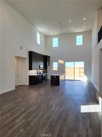 a view of an empty room with a kitchen and a window