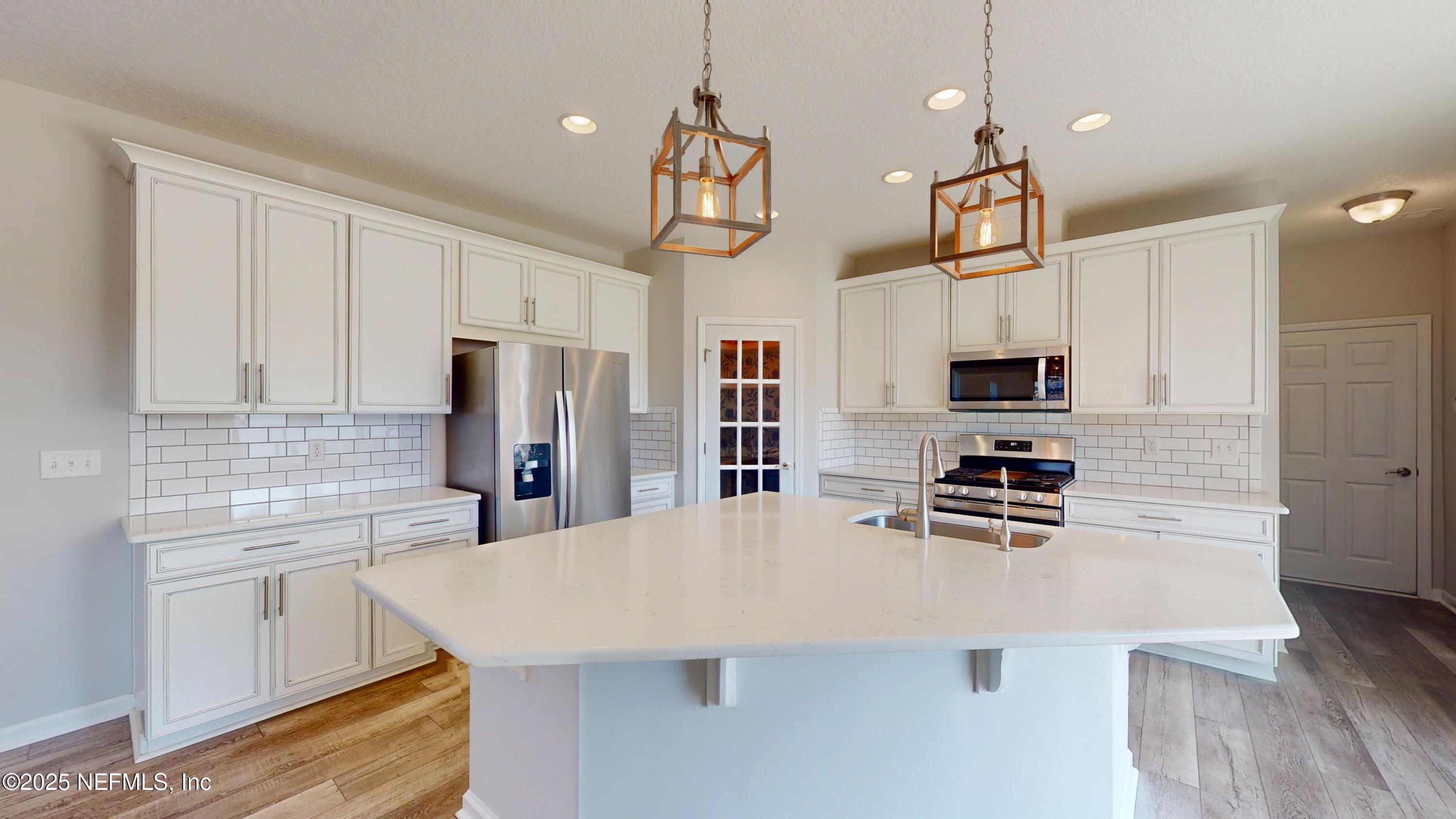 44 Footbridge Road St. Johns, FL 32259 - Photo 17 of 45 a kitchen with stainless steel appliances a stove a sink a refrigerator a center island a stove a refrigerator white cabinets and wooden floor