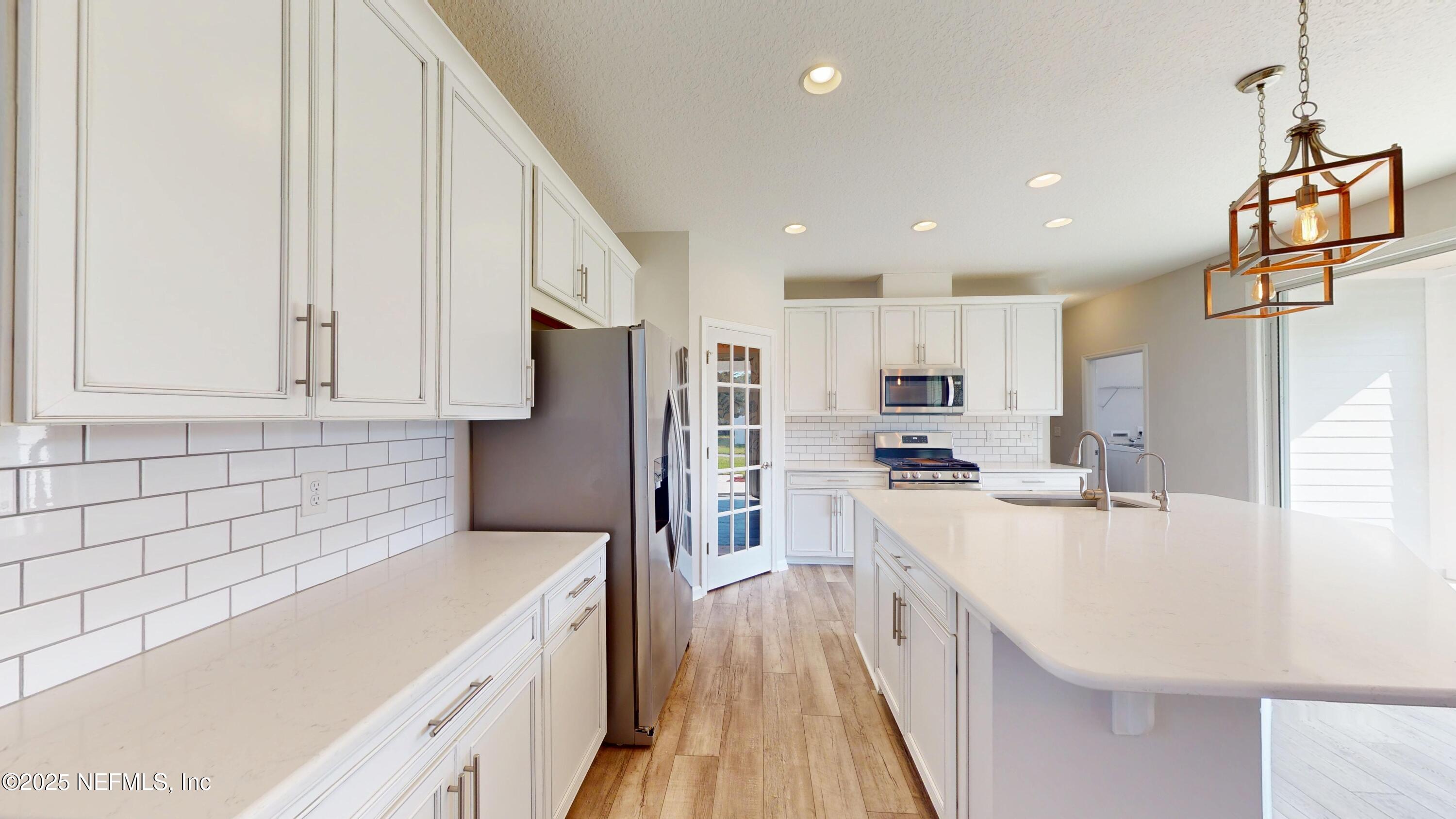 44 Footbridge Road St. Johns, FL 32259 - Photo 8 of 45 a kitchen with stainless steel appliances granite countertop a refrigerator a stove a sink and white cabinets with wooden floor