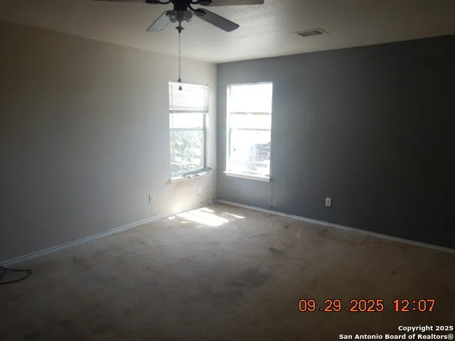 an empty room with windows and fan