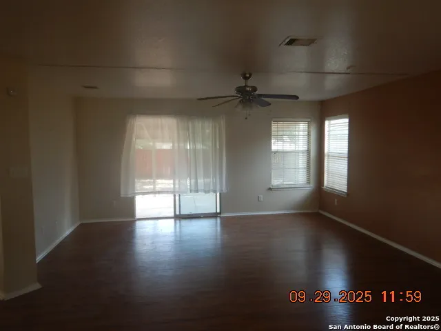 an empty room with wooden floor and windows