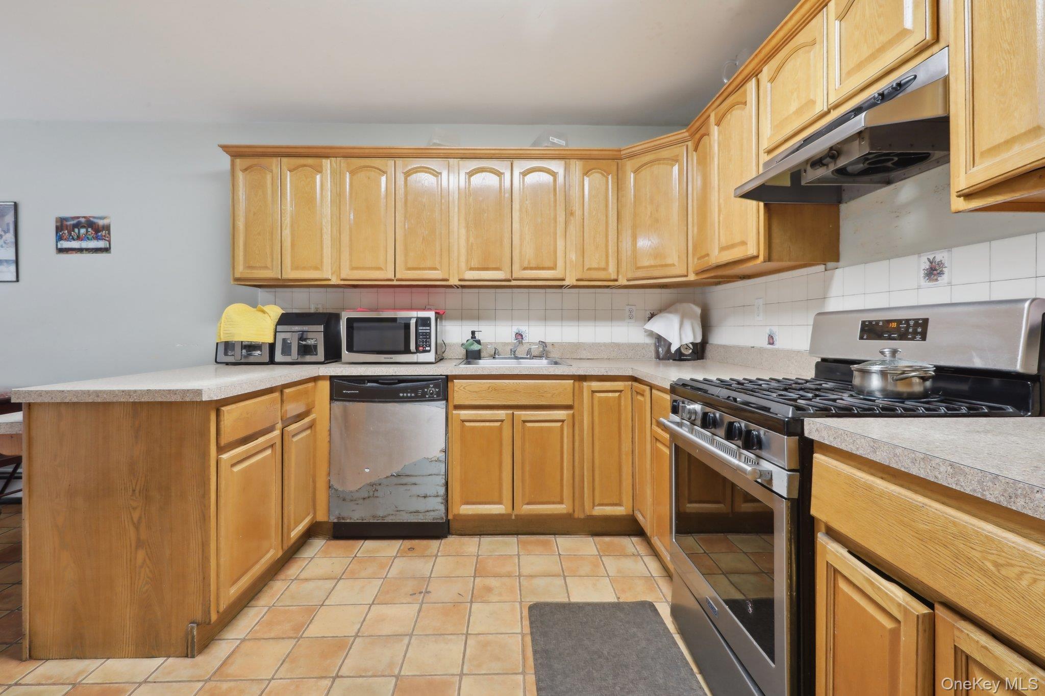 12-14 Lincoln Street Spring Valley, NY 10977 - Photo 17 of 39 a kitchen with a stove a sink and a refrigerator