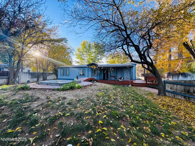 a view of a house with a yard tree and wooden fence
