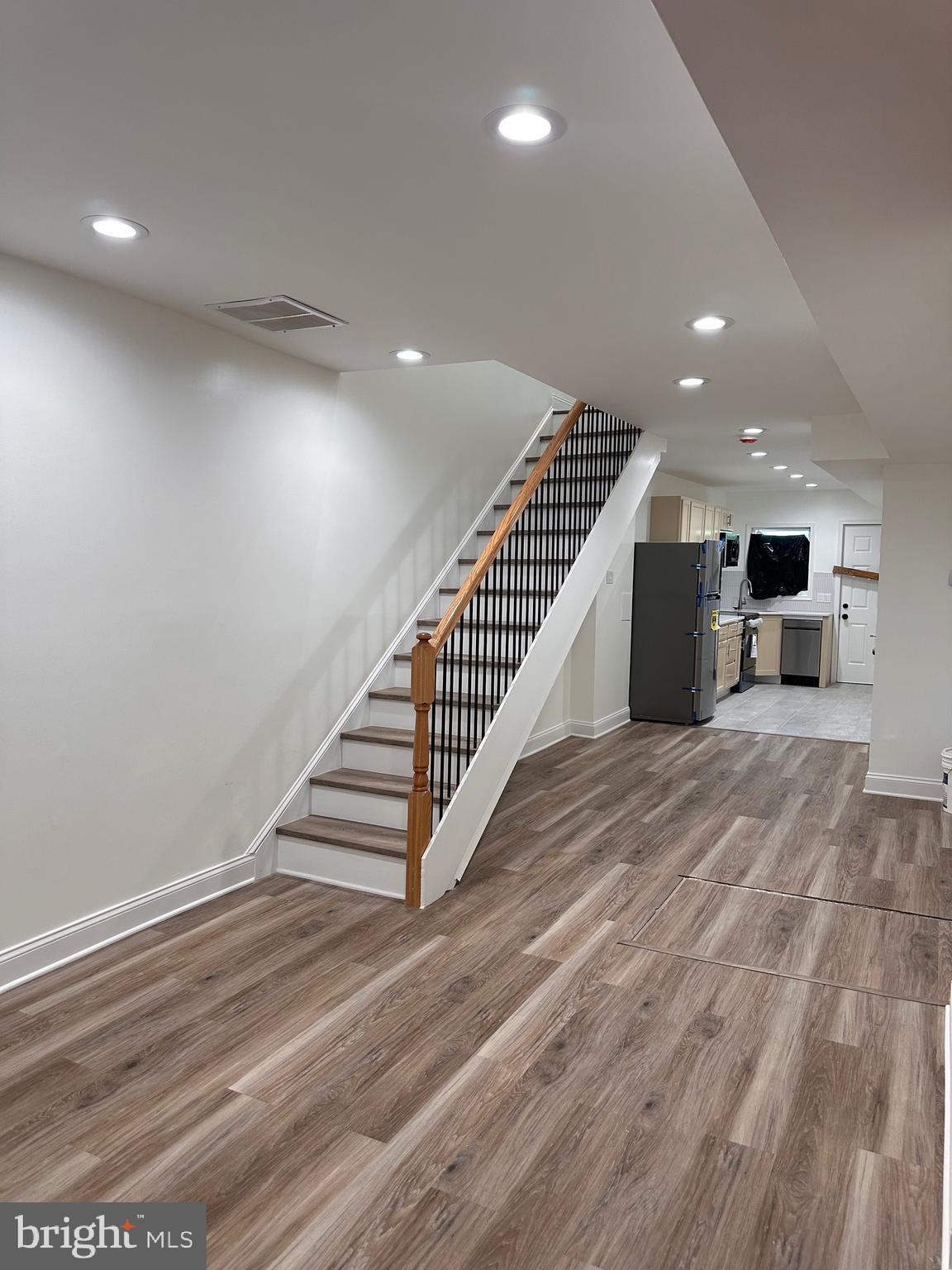 a view of a hall with stairs and wooden floor