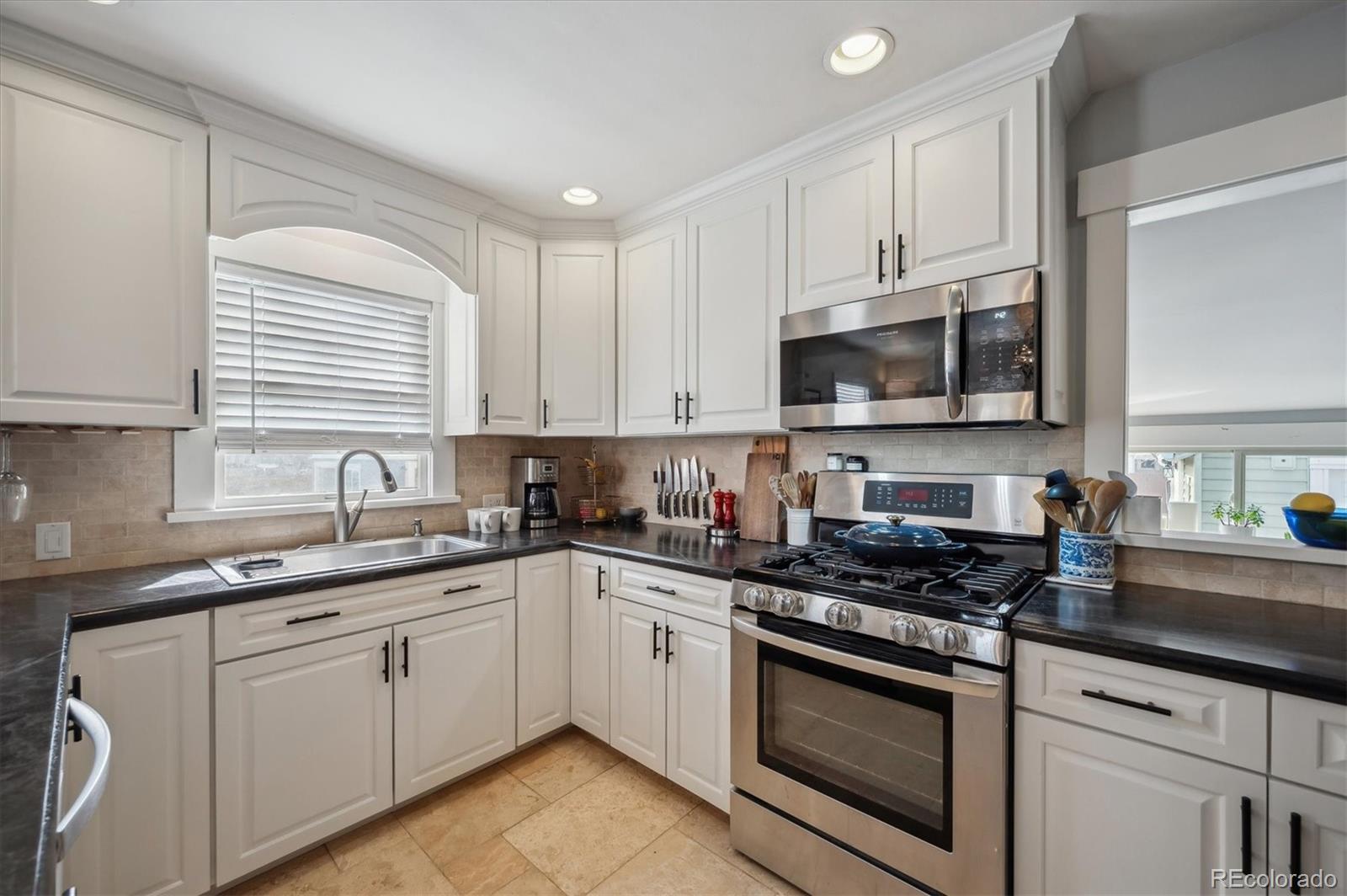 3885 Quay Street Wheat Ridge, CO 80033 - Photo 17 of 40 a kitchen with stainless steel appliances granite countertop white cabinets granite counter tops and a wooden floors