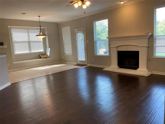 an empty room with wooden floor fireplace and windows