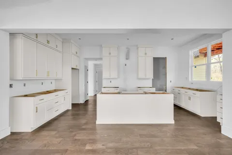 a large white kitchen with wooden floors and white cabinets