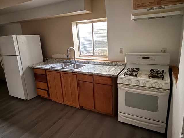 874 770 South Tooele, UT 84074 - Photo 13 of 19 Kitchen featuring wood-finish cabinetry, speckled countertops, and a double basin sink with a gooseneck faucet