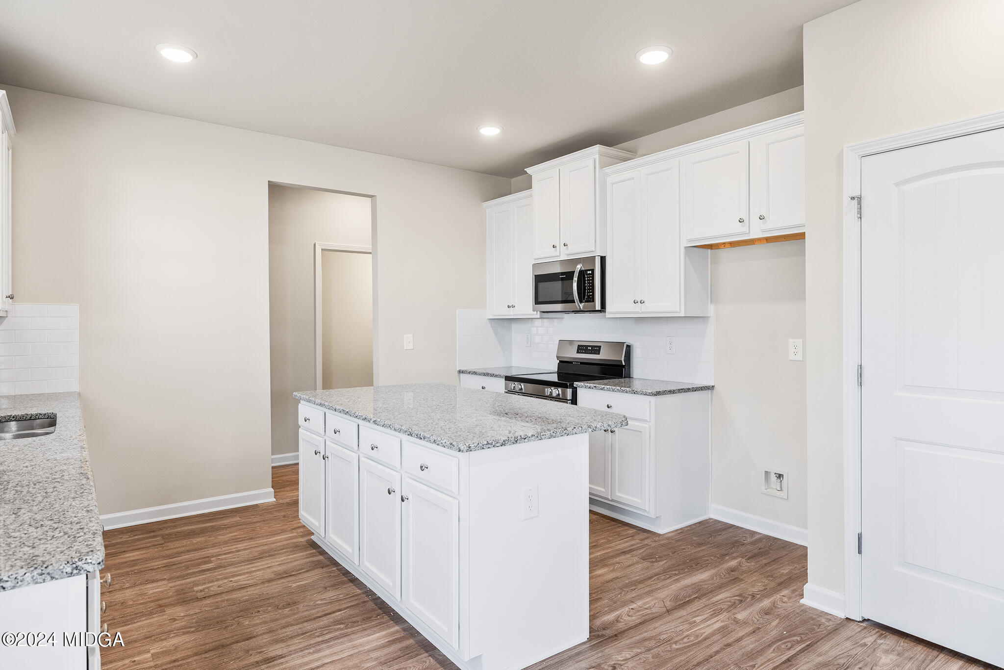 499 Grand Magnolia Street Jackson, GA 30233 - Photo 11 of 35 a kitchen with a sink a stove a refrigerator and white cabinets