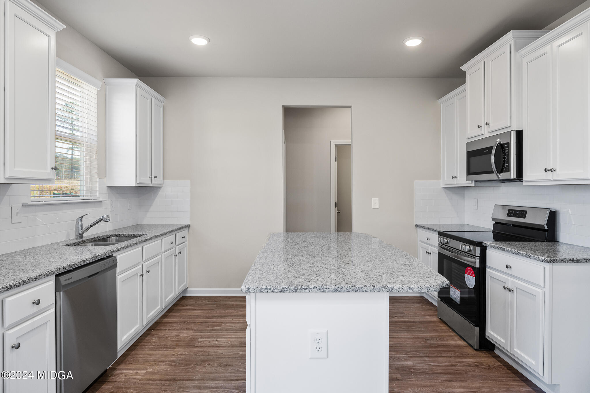 499 Grand Magnolia Street Jackson, GA 30233 - Photo 13 of 35 a kitchen with stainless steel appliances granite countertop a stove top oven a sink dishwasher and a microwave oven with large wooden cabinets