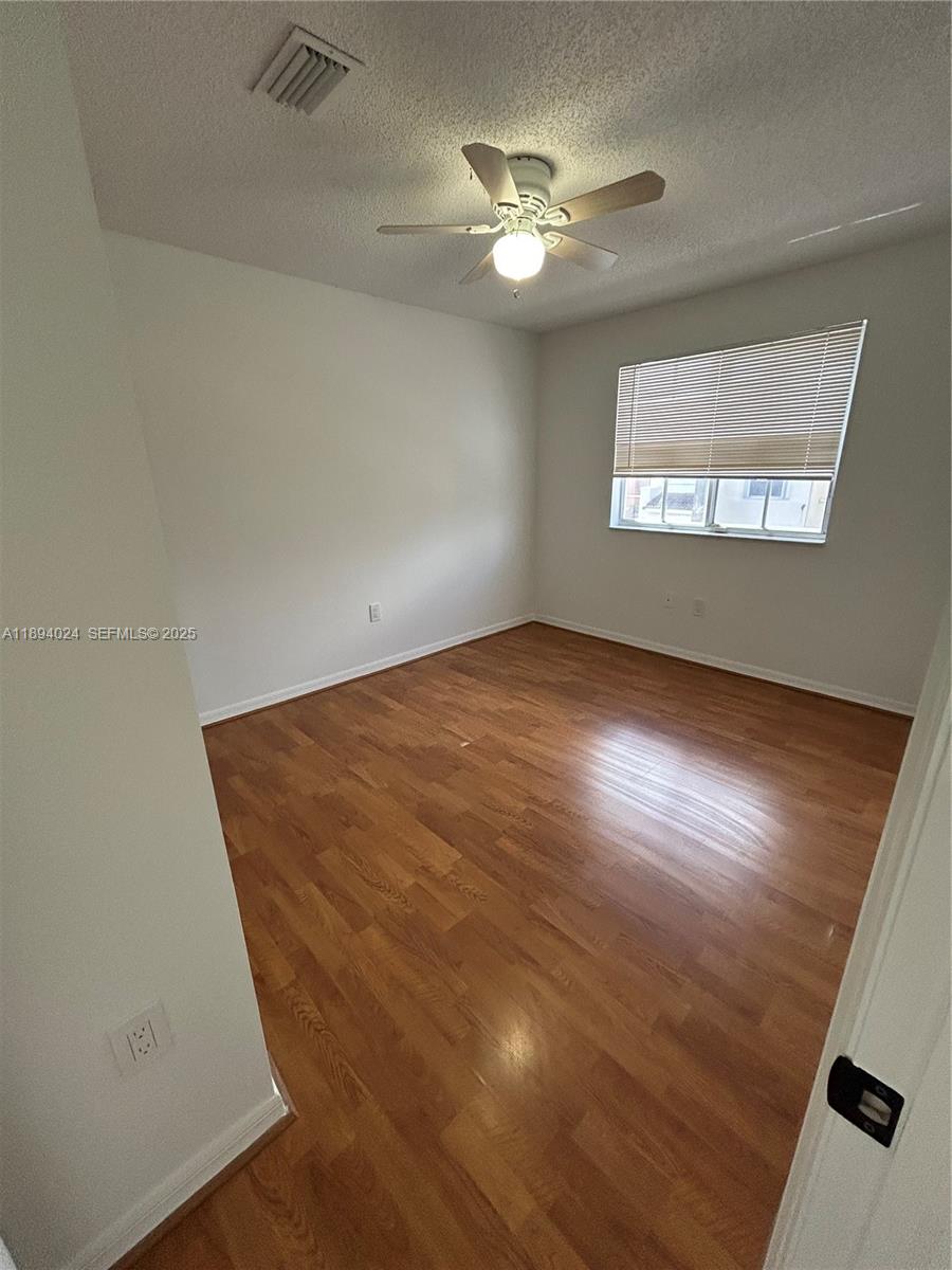 8725 Southwest 158th Place Miami, FL 33193 - Photo 32 of 53 an empty room with wooden floor chandelier fan and windows