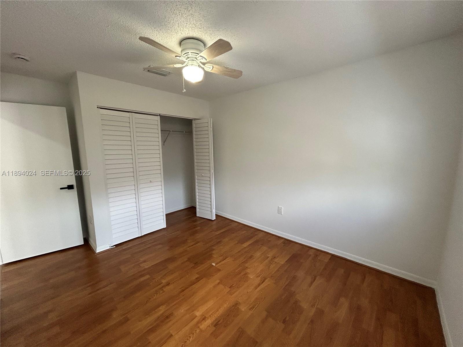 8725 Southwest 158th Place Miami, FL 33193 - Photo 34 of 53 an empty room with wooden floor and fan