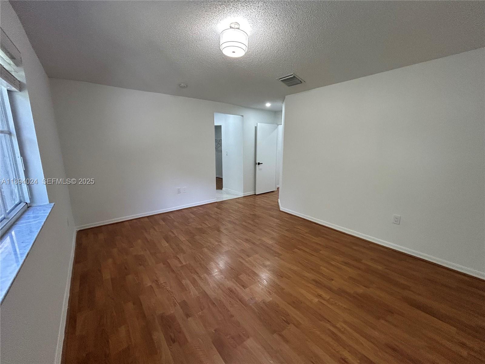 8725 Southwest 158th Place Miami, FL 33193 - Photo 38 of 53 a view of an empty room with wooden floor and a window