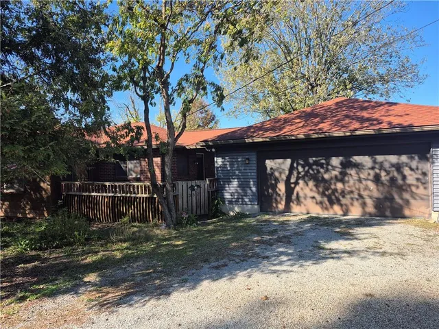a front view of a house with a large tree