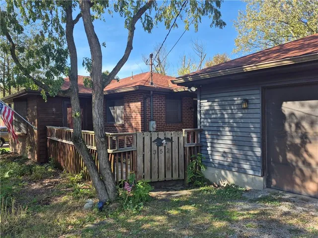 a view of a house with a small yard and a large tree