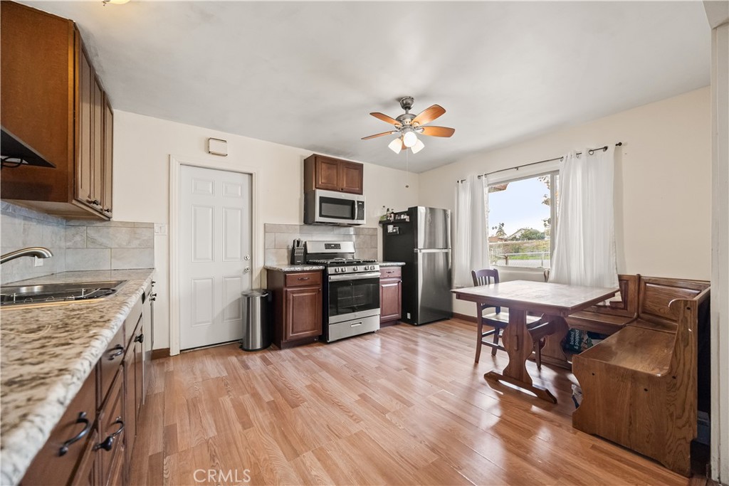 680 North 10th Street Banning, CA 92220 - Photo 5 of 24 a kitchen with stainless steel appliances granite countertop a stove top oven a sink dishwasher a dining table and chairs with wooden floor
