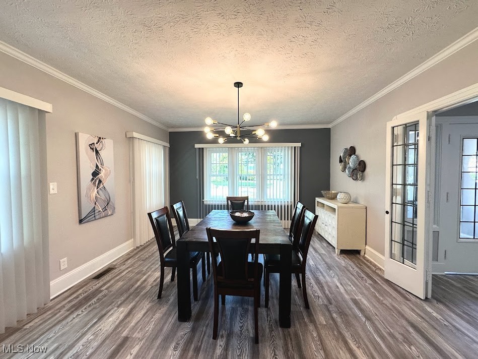 3190 Warrington Road Cleveland, OH 44120 - Photo 7 of 21 Dining space with a textured ceiling, wood finished floors, a chandelier, and ornamental molding