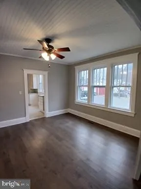 an empty room with windows and ceiling fan